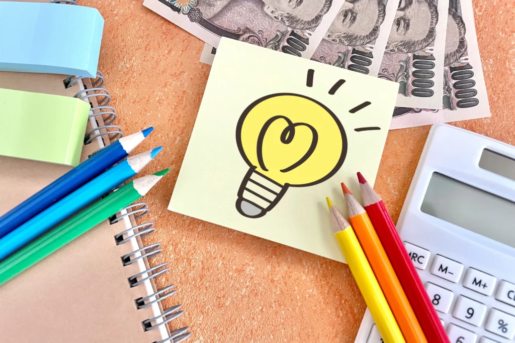 消防設備工事の費用相場のアイデアをイメージする電卓と紙幣、付箋の電球イラスト